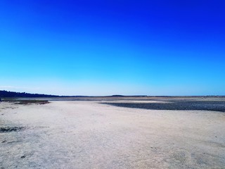 A sandbank next to the estuary. Blue sky, horizon and large sandbank.