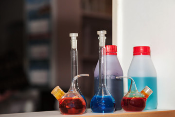Group of flasks and test tubes in chemical laboratory. Reagents and samples acid suspensions on laboratory table for experiments. Various conical flasks with samples of different colors in interior