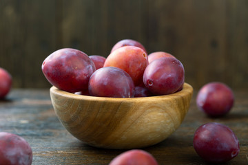 Fresh plums in a wooden bowl. Harvesting.