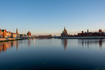 Fototapeta na wymiar Russia, Yoshkar-Ola, July 24, 2020, view from the bridge at sunset, the Kremlin and the Kokshaga river, reflection in the water.