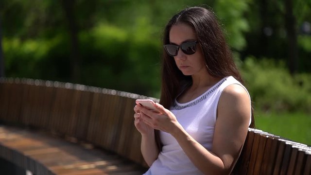 Close-up of one woman in sunglasses walking in the Park writing a text message. portrait of confident seriousness