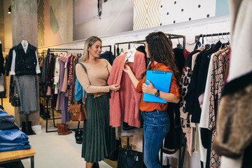 Female seller helps buyer to choose between diferent clothes.