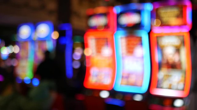 Defocused slot machines glow in casino on fabulous Las Vegas Strip, USA. Blurred gambling jackpot slots in hotel near Fremont street. Illuminated neon fruit machine for risk money playing and betting.