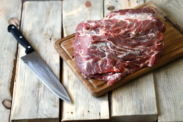 Selective focus. Raw meat on a board and a knife. Pork neck.