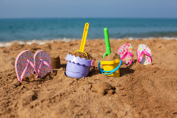 Sandbox for children on the beach. Slippers, buckets and shovels on the beach.