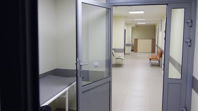 Panning shot of interior of empty hallway of modern clinic with reception desk and comfortable bench and chair