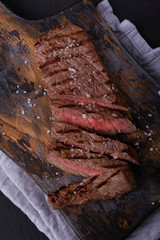 Sliced beef steak seasoned with salt on cutting board