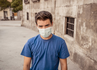 Portrait of young sad man with protective surgical face mask in public spaces in the new normal