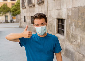 Portrait of young happy man with protective surgical face mask in public spaces in the new normal