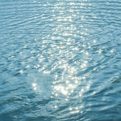 Sun glare on the water. Blue water summer background. Blur.