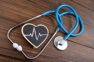 Workplace of a doctor. Stethoscope and little heart on wooden desk background