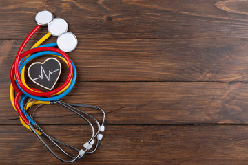 Workplace of a doctor. Colorful Stethoscopes and little heart on wooden desk background -...