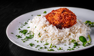 roasted burger with rice in white plate on black wooden table background