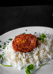 roasted burger with rice in white plate on black wooden table background