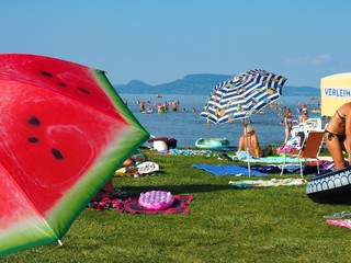 Balatonmáriafürdő, Hungary - July 29, 2020: Colorful umbrellas, sunbathing and bathing people on the beach of the lake Balaton, Hungary in hot July day - obrazy, fototapety, plakaty
