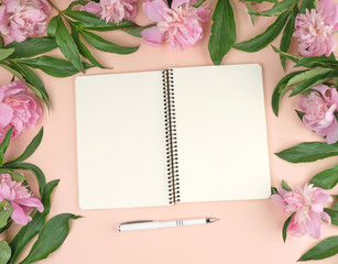 open spiral notepad with white blank sheets and a bouquet of pink peonies