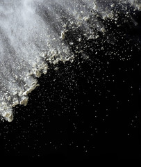 cloud of white wheat flour on a black background, particles fly in different directions