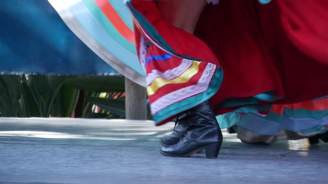 Latino women in colourful traditional dresses dancing Jarabe tapatio, mexican national folk hat dance. Street performance of female hispanic ballet in multi colored ethnic skirts. Girls in costumes.