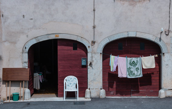 fa&ccedil;ade ancienne ferme avec deux grandes portes en bois rouges, chaise et linge &agrave; s&eacute;cher dans le Jura en France