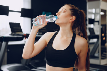 Young sporty woman drinking water in a gym