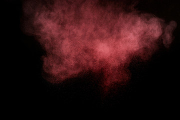 Red and pink powder explosion on black background. Colored powder cloud. Colorful dust explode. Paint Holi.