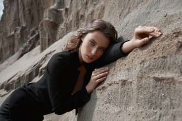 Fashion sexy woman in a suit posing on sand rocks. Modern independent girl, beautiful makeup