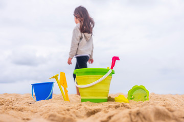Une petite fille à la mer avec des jeux de plage dans le sable