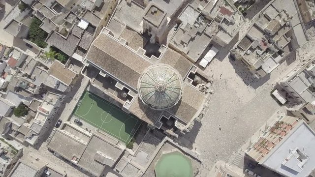 Aerial spinning zoom out view of Basilica Minore Pontificia Santissimo Rosario in Francavilla Fontana Puglia Italy. Italian religion, church baroque architecture. Sport ground cathedral. Cityscape.