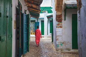 Unknown woman in national clothes on the old street in Tetouan Medina quarter in Northern Morocco....