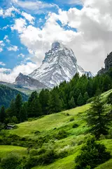 Tuinposter Vertical scenic view of the Matterhorn mountain summit with snow clouds blue sky and nature during summer in Zermatt Switzerland © Keitma