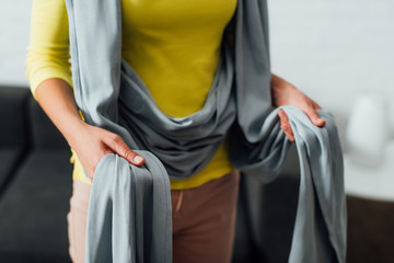 Cropped view of mother holding baby sling at home