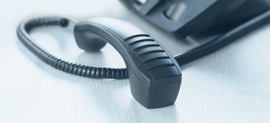 business and communications. voip phone in the office, with receiver off. Conference call, contact us or hotline banner. IP telephony, Telemarketing. Help desk or call centre. Cold calling banner
