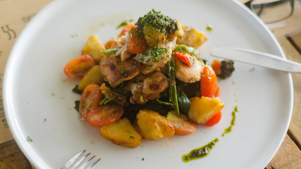 Chicken with potatoes and vegetables on a white plate in a restaurant