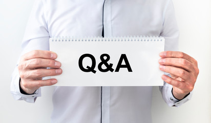 Q and A - Questions and Answers - sign on paper shown by a businessman