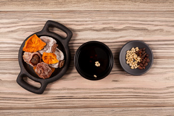 Sujeonggwa is a traditional Korean drink. Fruit punch. It is made from dried persimmons with the addition of cinnamon, ginger and pine nuts. Wooden background, copy space