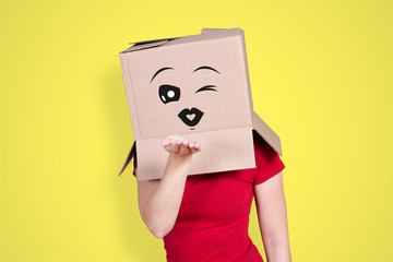 Person with cardboard box on its head and an amorous face expression blowing someone a kiss on...