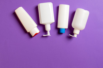 Set of White Cosmetic containers isolated on colored background, top view with copy space. Group of plastic bodycare bottle containers with empty space for you design