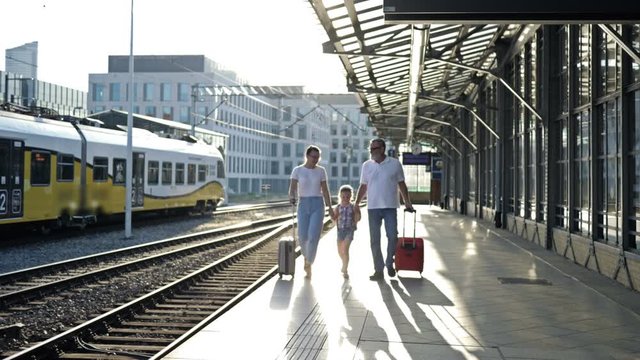 An elderly man with his daughter and little vuchka are walking along the platform. The passengers are holding suitcases. Good mood.