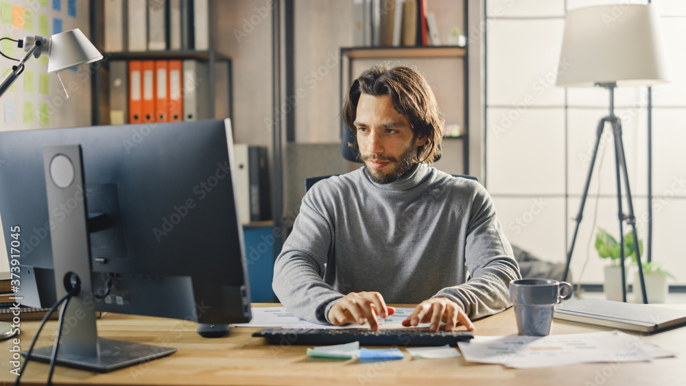 Poster creative entrepreneur sitting at his desk works on desktop computer in the stylish office. handsome 