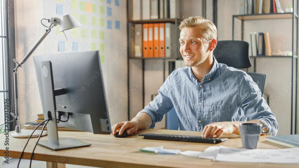 Poster creative entrepreneur sitting at his desk works on desktop computer in the stylish office. handsome 
