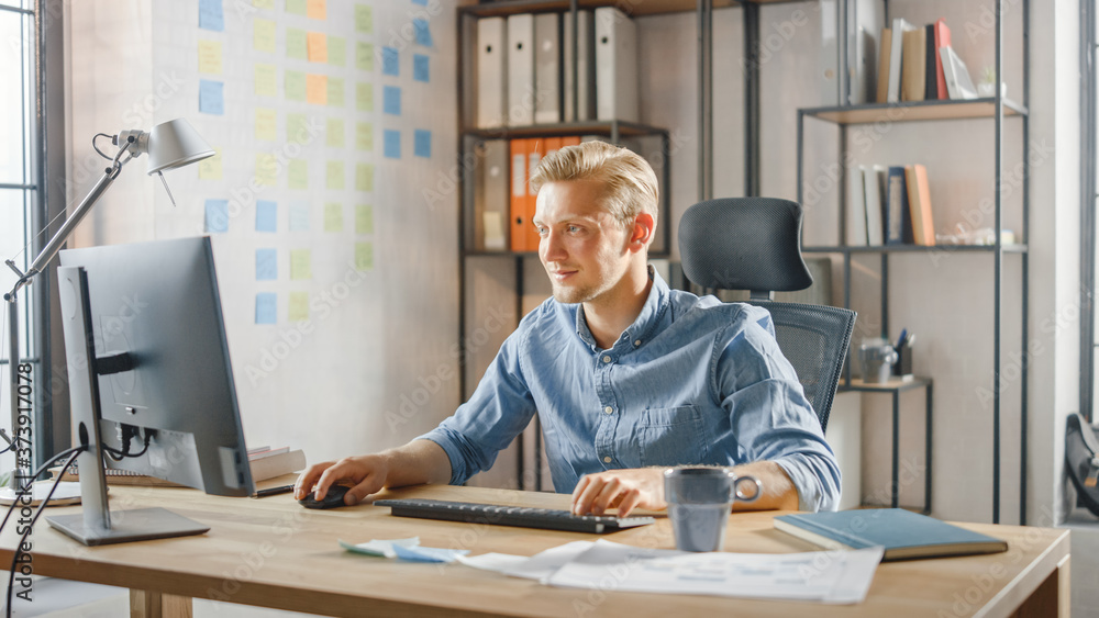 Canvas Prints Creative Entrepreneur Sitting at His Desk Works on Desktop Computer in the Stylish Office. Handsome Young Businessman Uses Computer, Does Outsourcing Job, Designs New Apps and Develops Software