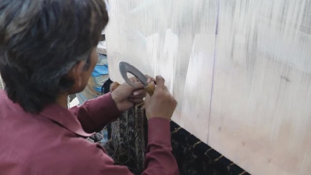 high frame rate clip of a worker hand knotting a carpet at a factory in agra, india