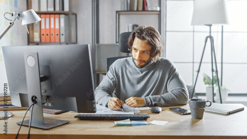 Aufkleber handsome long haired entrepreneur sitting at his desk in the office works on desktop computer, worki