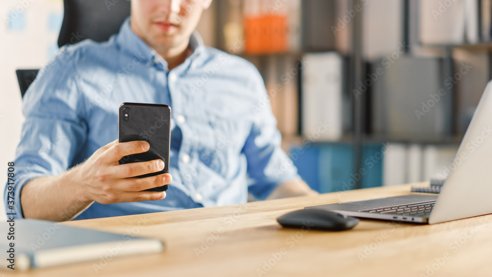 Aufkleber businessman sitting at his desk works on desktop computer in the stylish office and using smartphone