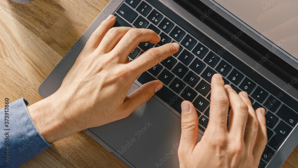 Poster top view close-up shot of a man's hands typing on a laptop keyboard. bright and modern theme.