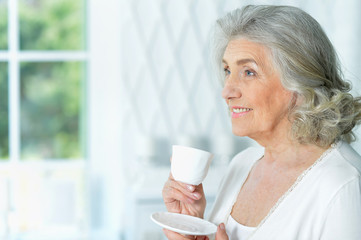 Close up portrait of beautiful smiling senior woman drinking tea
