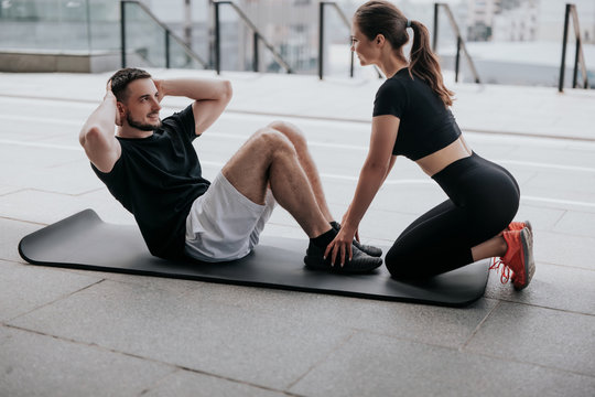 happy young couple handsome brunette man and beautiful woman in sportswear warming up before street workout, healthy fit lifestyle