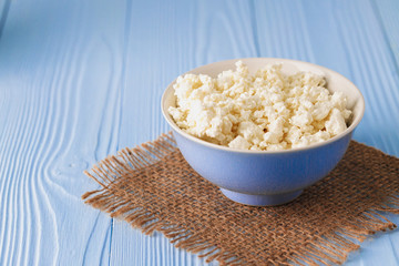 Cottage cheese in bowl on blue wooden background