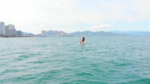 Extreme water sport and summer vacations concept. Professional kite surfer on the sea wave, athlete showing sport trick jumping with kite and board in air.