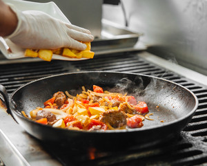 Restaurant chef cooking meat with vegetables 